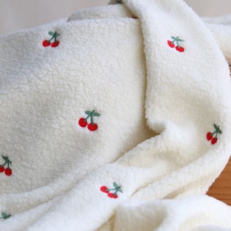 Teddy / moumoute bouclé fond écru broderies cerises