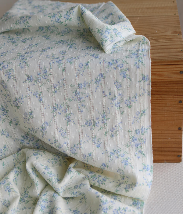 Broderie anglaise plumetis en coton imprimé fleuri bleu sur fond écru