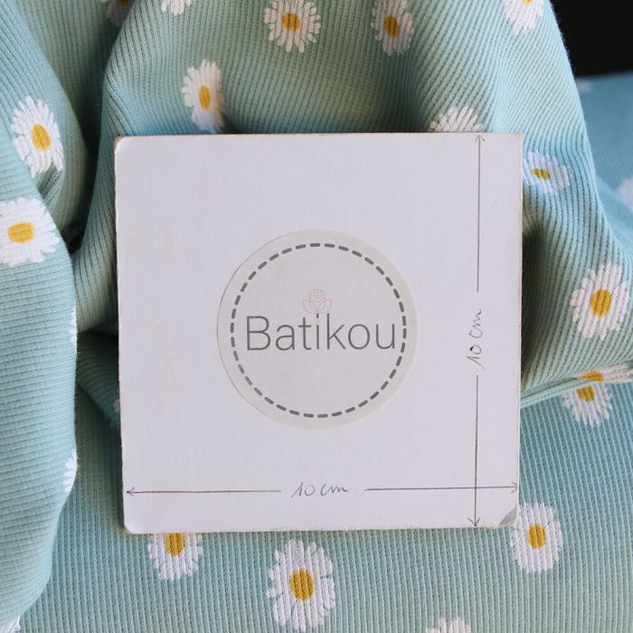 Jersey coton côtes fines à motif marguerites sur fond vert tendre