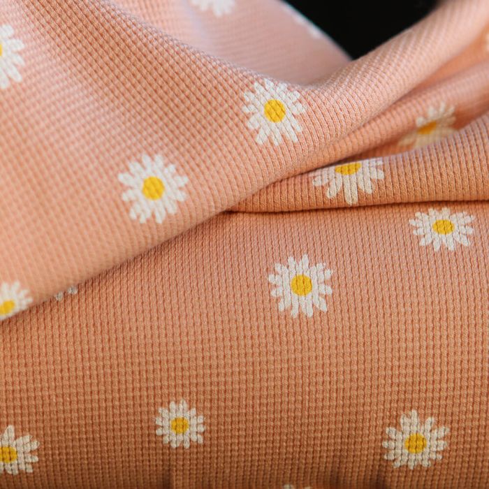 Jersey coton gaufré côtes fines à motif marguerites sur fond pêche nude
