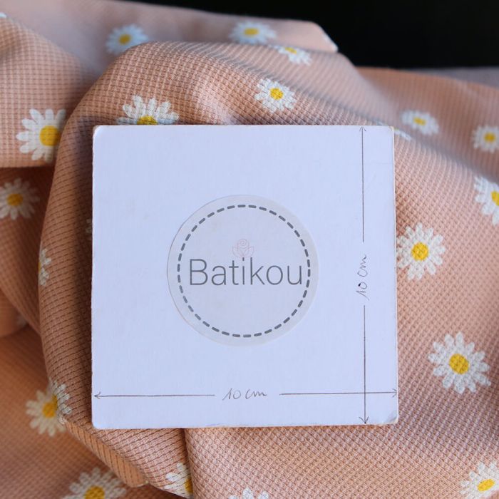 Jersey coton côtes fines à motif marguerites sur fond pêche nude