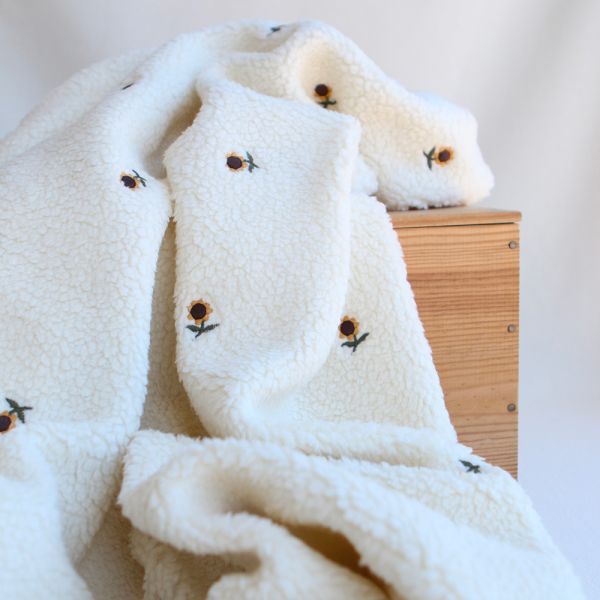 Tissu teddy écru bouclé brodé de petits tournesols jaunes, fausse laine mouton