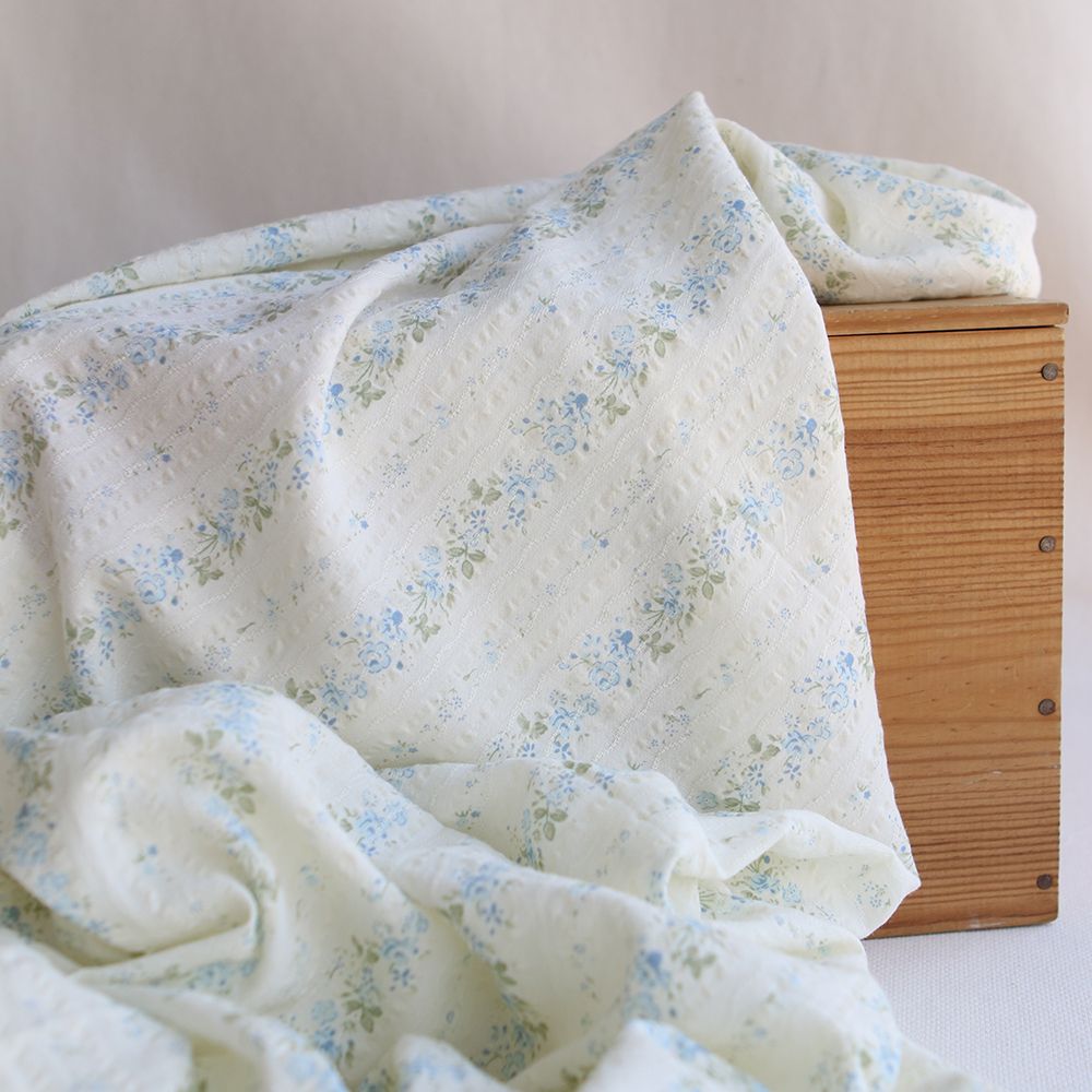 Camille - Tissu coton jacquard seersucker fond écru fleuri bleu clair